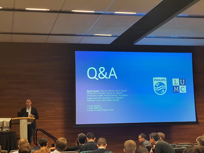 Презентация Nicola Pezzotti (главный автор данной работы и статьи)  на NeurIPS’19. Слайд с перечислением авторов.  Nicola отвечает на вопросы из зала